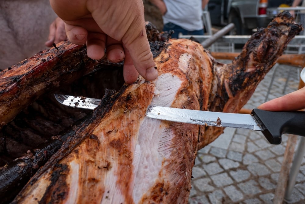 Chef,Slicing,Pork,On,A,Spit,At,An,Outdoor,Event