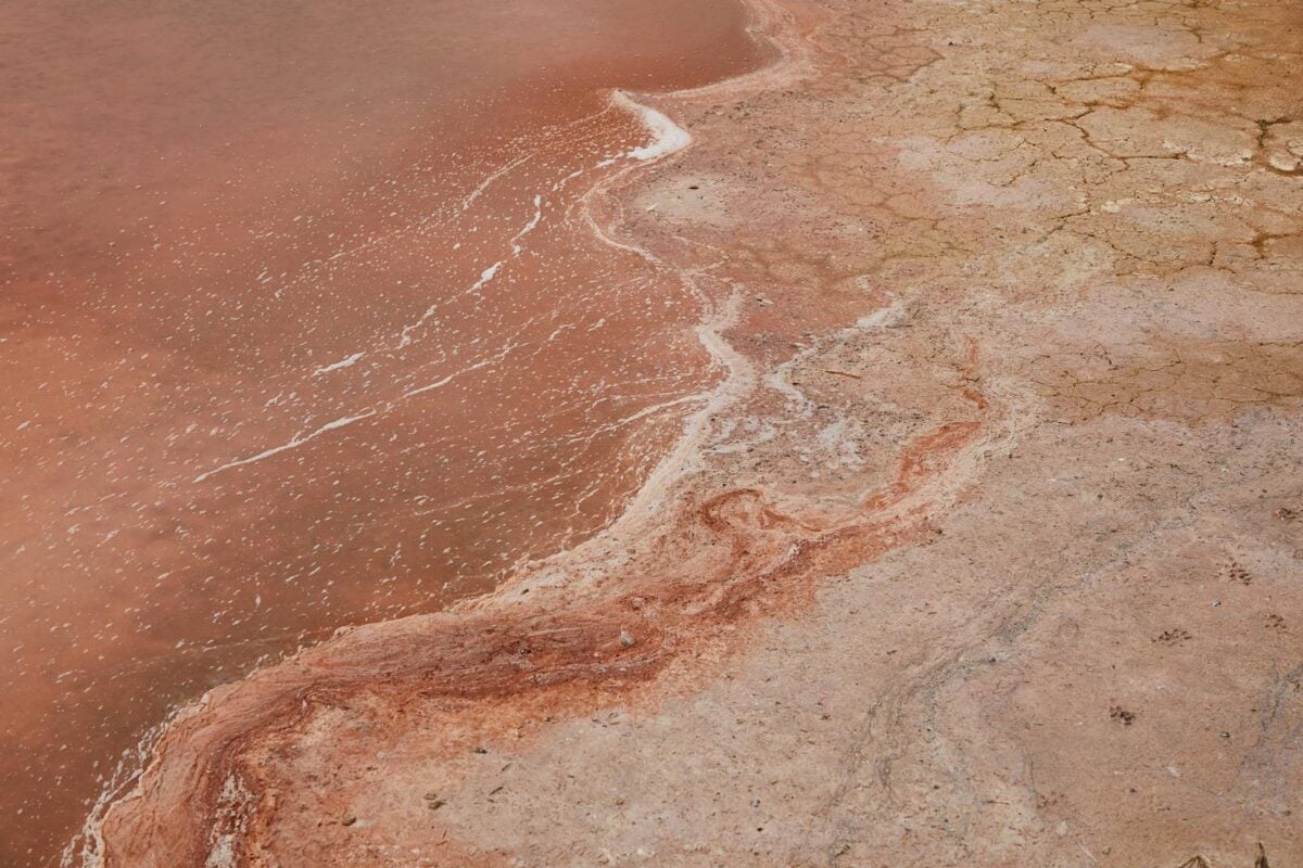 From above of uneven coast with cracks washed by tranquil water of ocean
