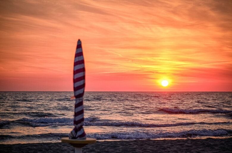 Vibrant sunset over Durres beach, Albania, with vivid orange skies and gentle waves.