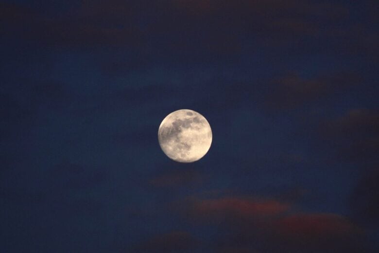 Beautiful full moon against a dark, cloudy night sky, offering a serene lunar view.
