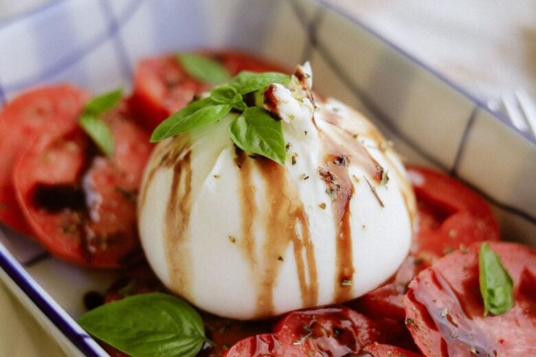 Delicious caprese salad with burrata, tomatoes, basil, and balsamic glaze.