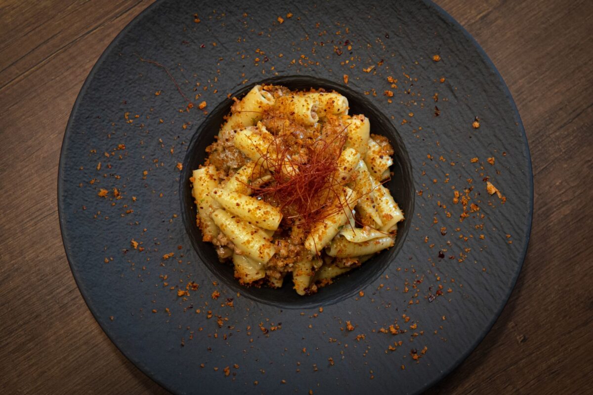 Delicious rigatoni pasta with spices served on a rustic black plate.