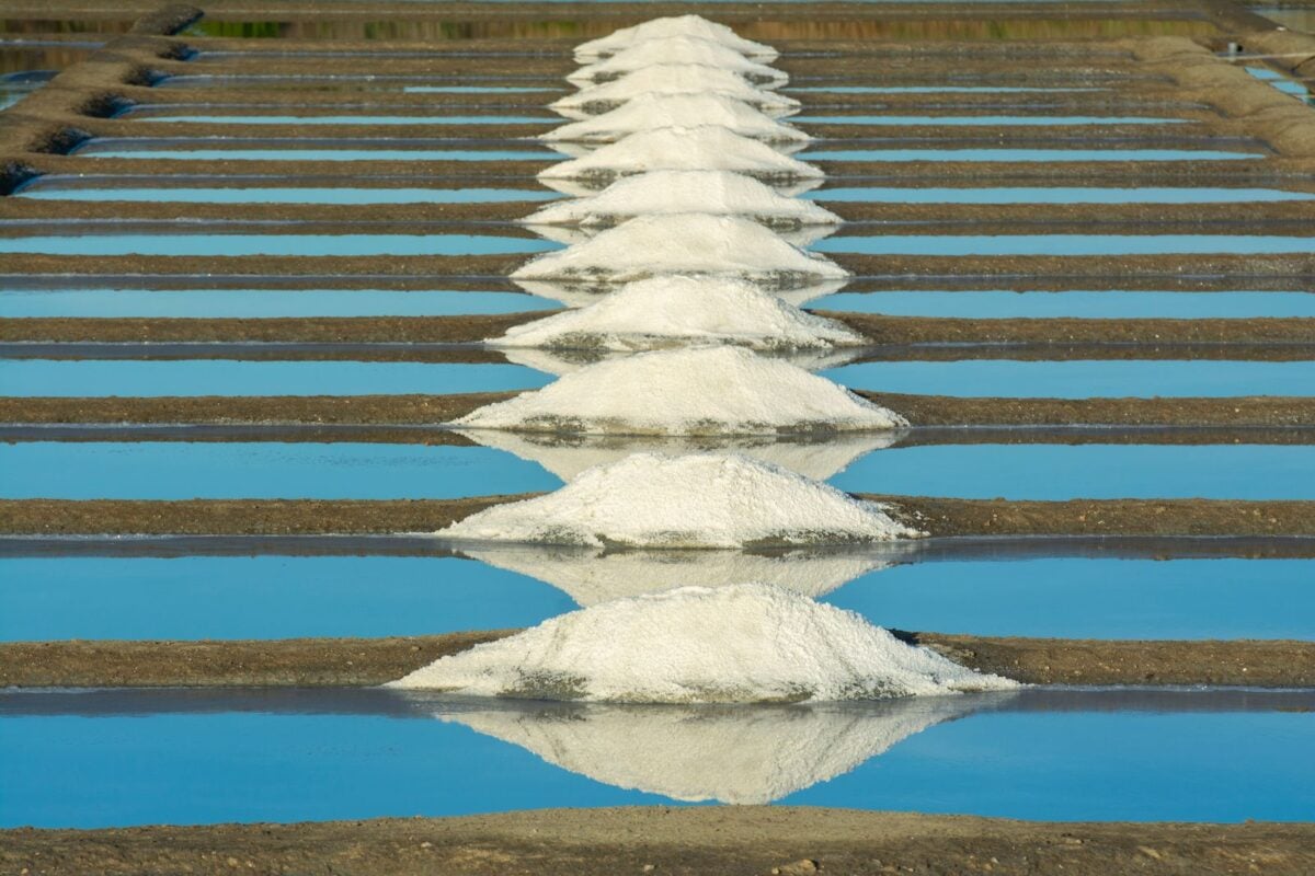 Aerial view of Guérande salt pans in France with white salt mounds reflecting in the water.