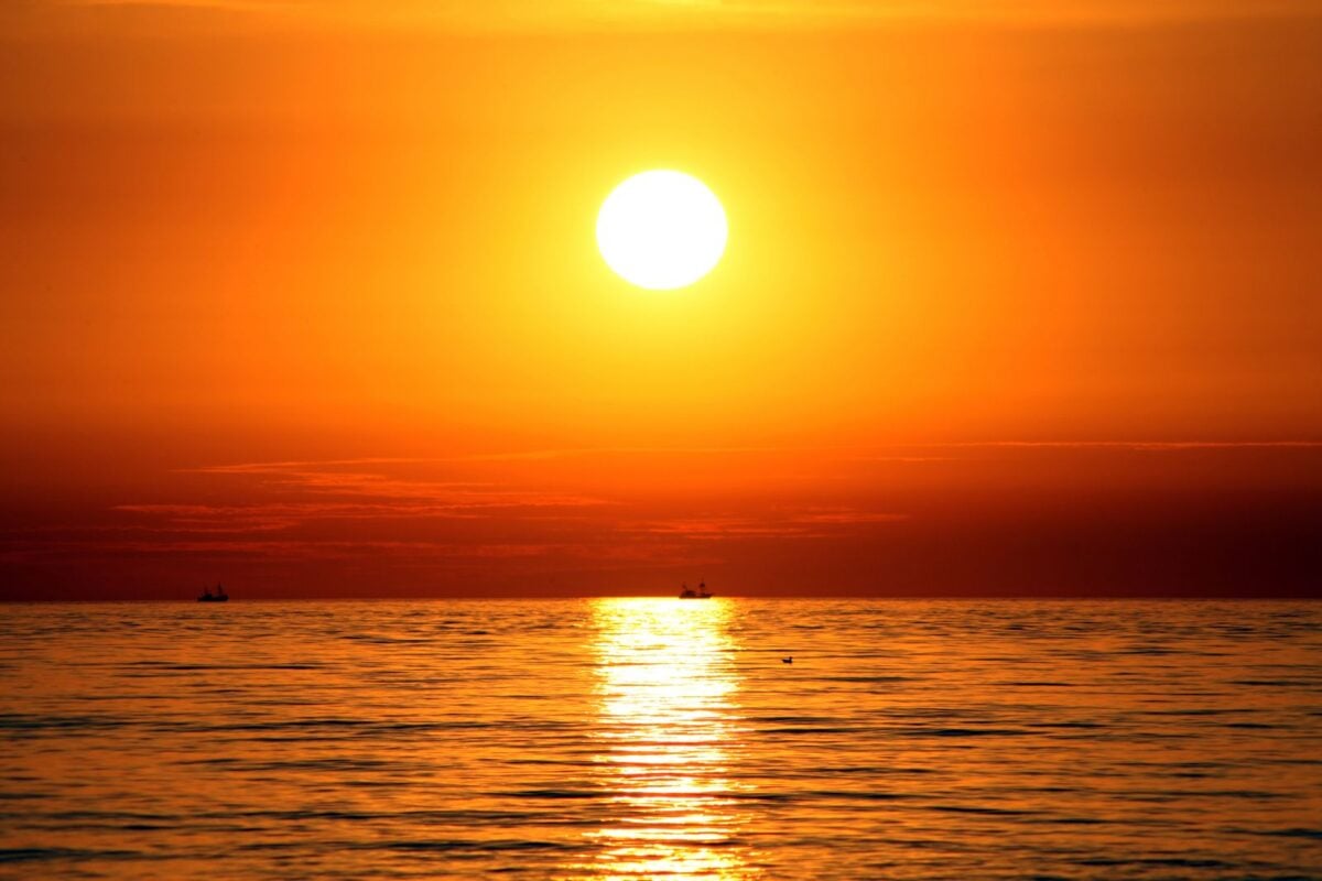 Vibrant sunset over the sea in Spain, reflecting warm hues on tranquil waters.