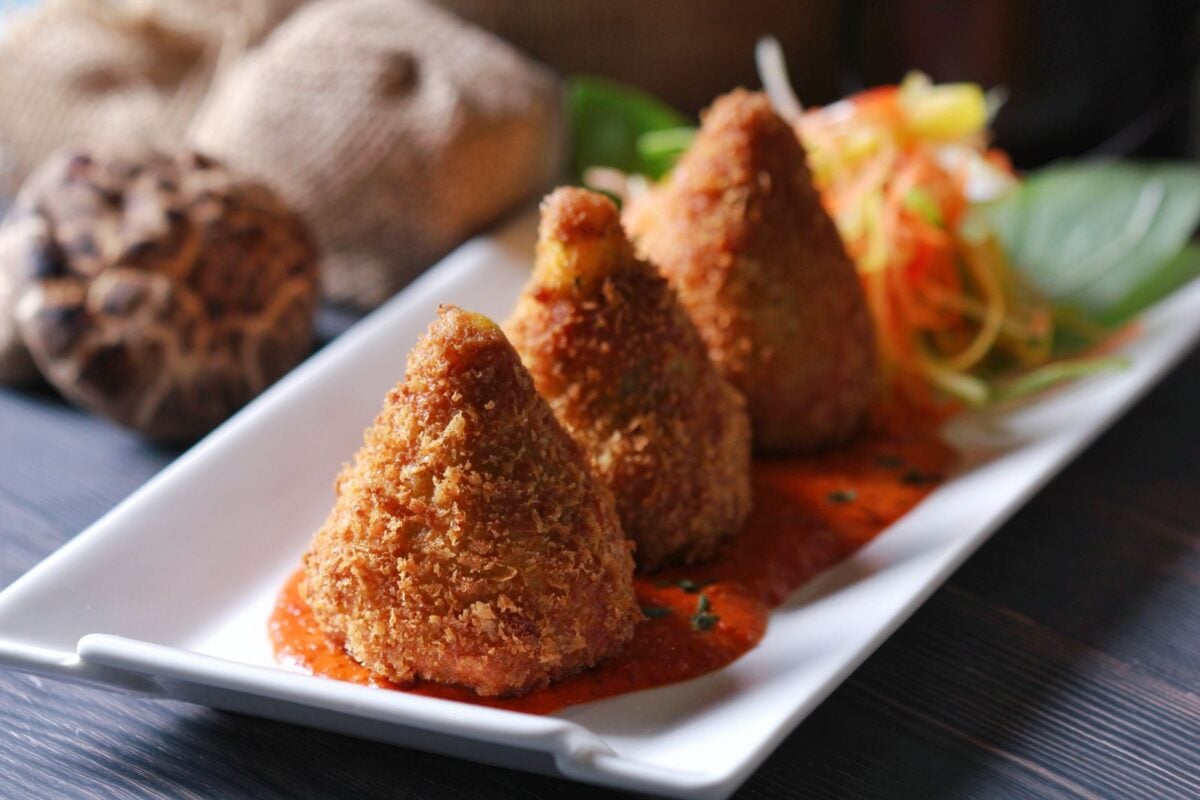 Delicious crispy fried snacks served on a white plate with sauce and salad garnish. Perfect appetizer.