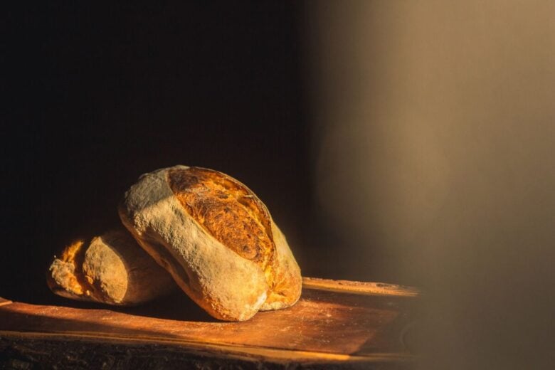 A close-up of rustic artisan bread illuminated by warm sunlight, capturing its texture and crust.