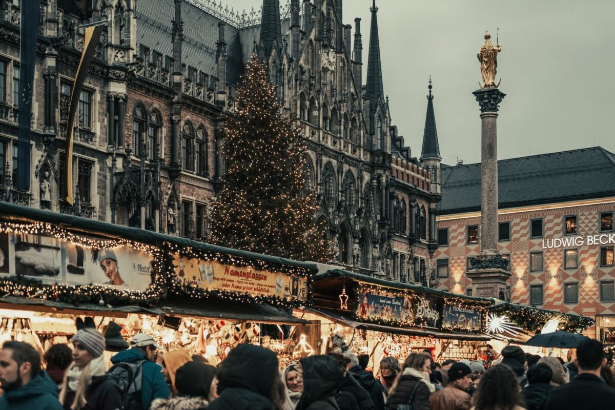 Crowded Christmas market at Marienplatz in Munich, showcasing holiday lights and festive stalls.