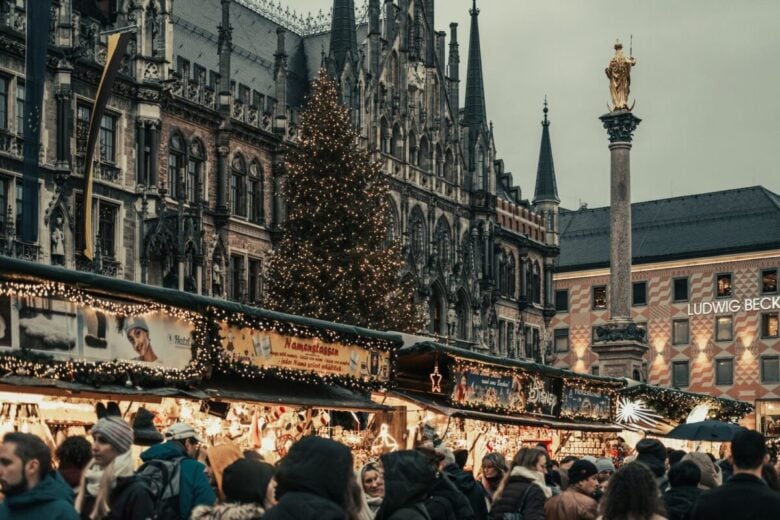 Crowded Christmas market at Marienplatz in Munich, showcasing holiday lights and festive stalls.