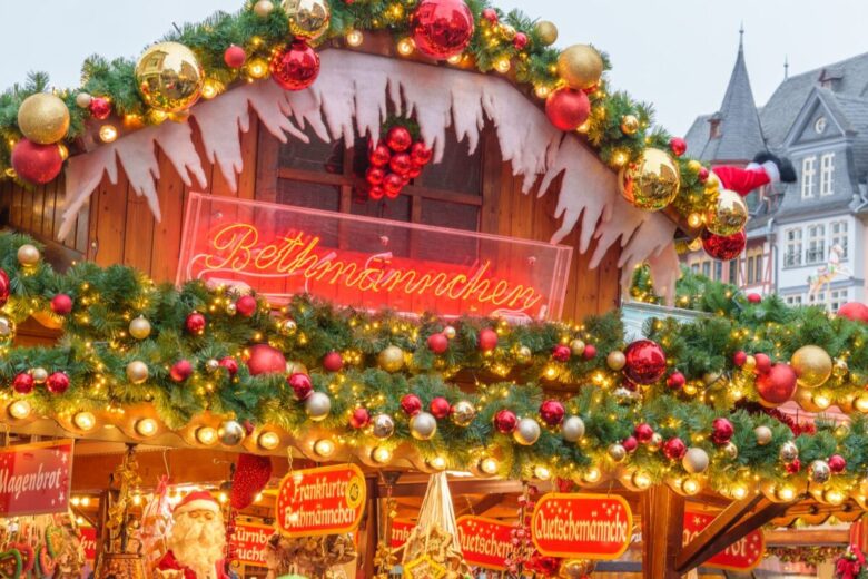 A festive Christmas market stand adorned with lights and holiday decorations at twilight.