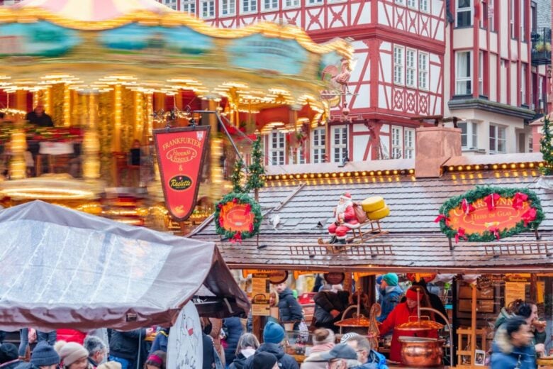 A vibrant scene at Frankfurt's Christmas market with people, carousel, and festive decorations.
