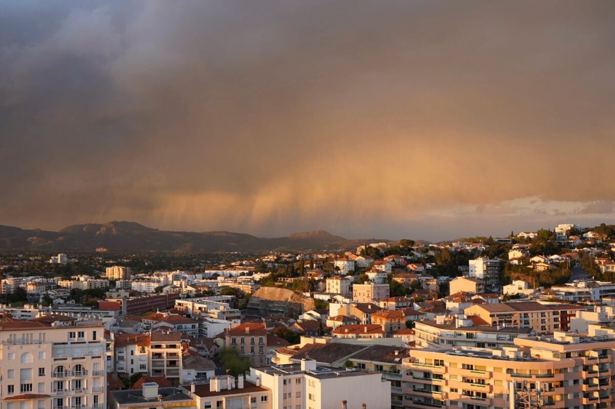 A cityscape view captures dramatic storm clouds and sunset hues, creating a striking scene.