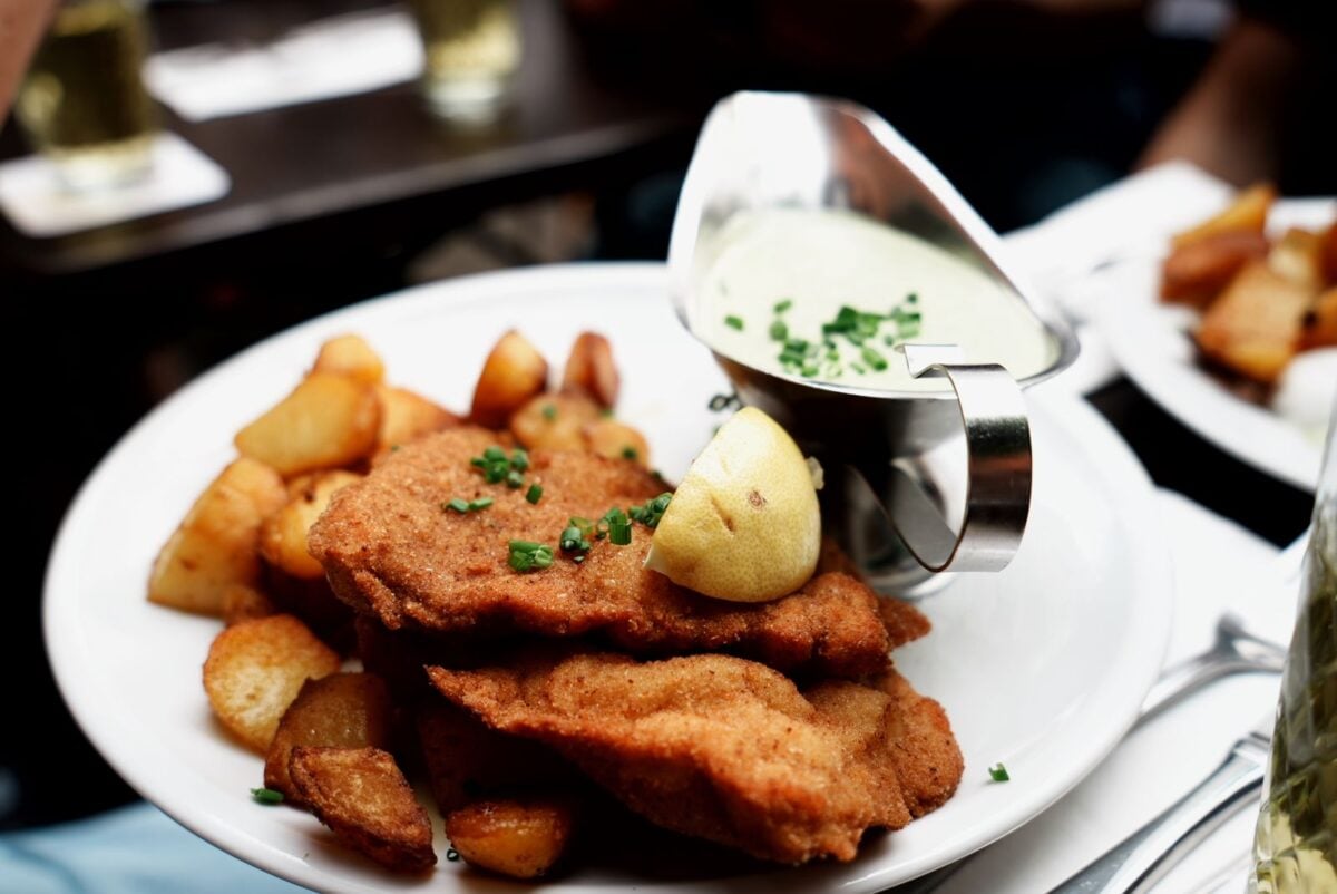 Tasty schnitzel served with roasted potatoes and lemon, complemented by creamy sauce.