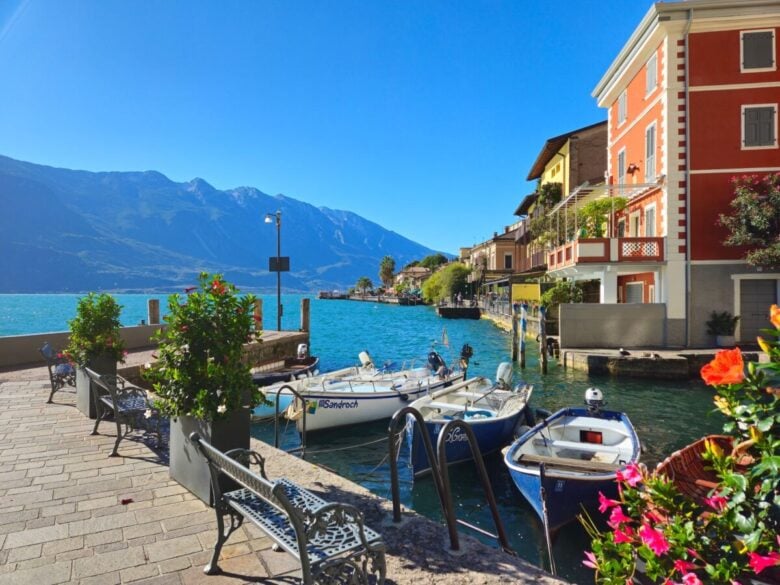 Beautiful view of Limone sul Garda with colorful boats and mountains under a clear blue sky.
