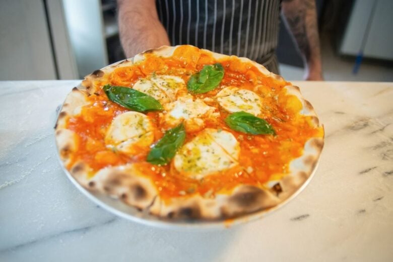 Close-up of a freshly baked Margherita pizza topped with basil leaves, ready to savor.