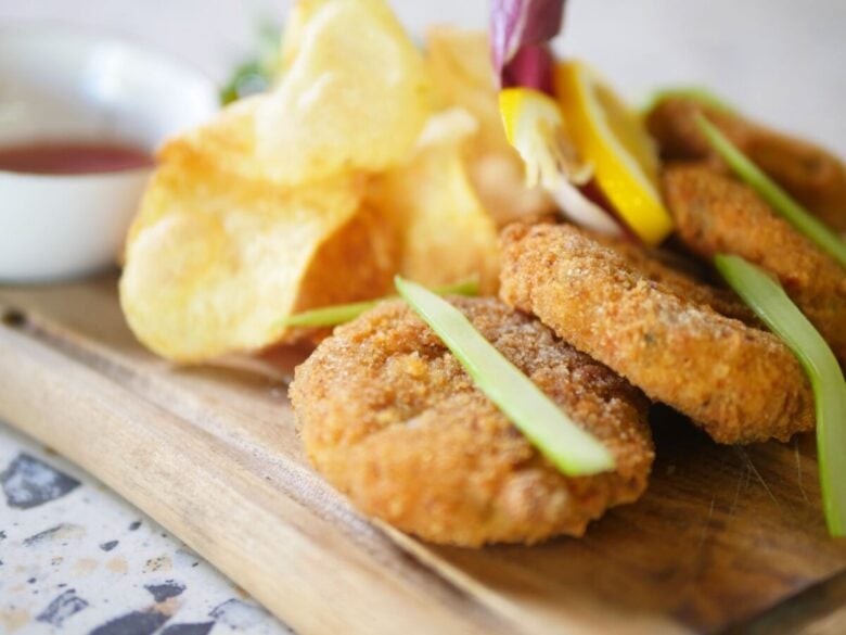 Close-up of delicious fried fish cakes with chips on a wooden board, perfect for a tasty meal.