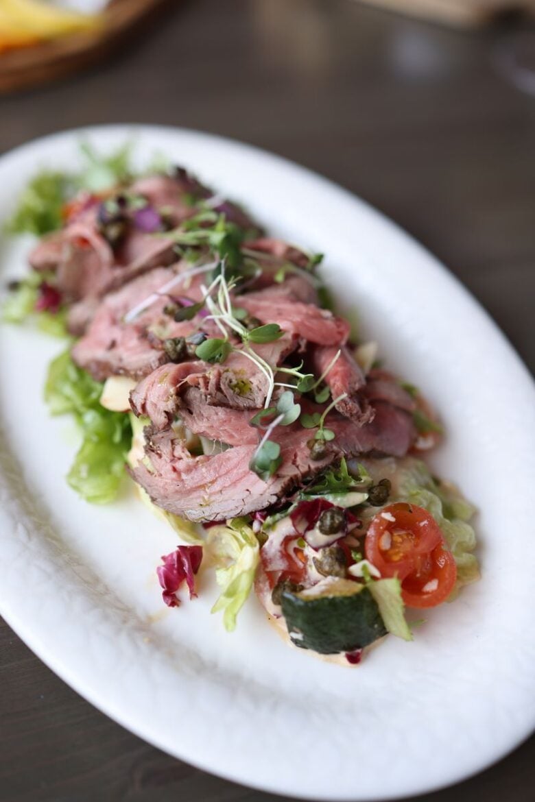 Delicious roast beef salad garnished with fresh microgreens and vegetables.